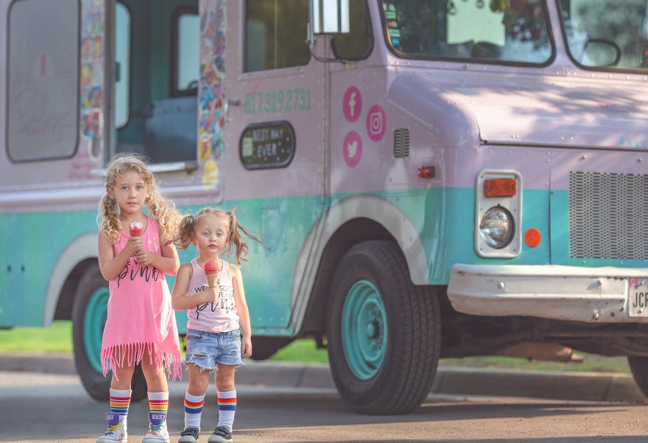 Toddler wearing Love rainbow tube socks outdoors by the old school food truck