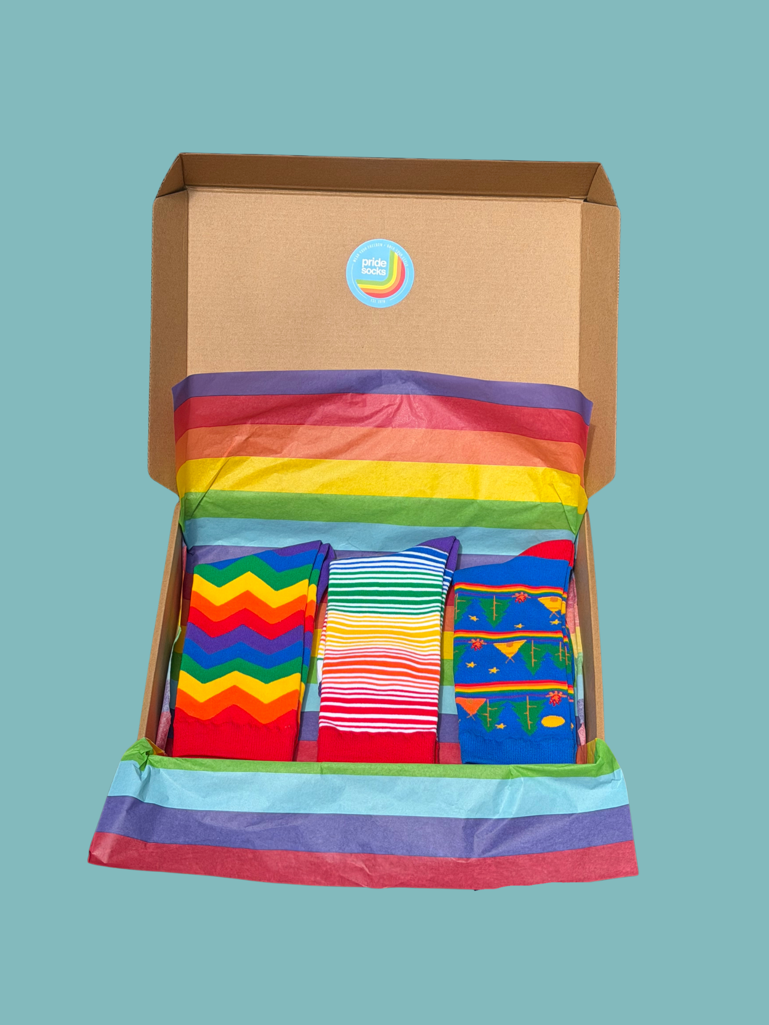 Open cardboard box with colorful socks on a solid background for gifting to someone coming out at work proudly