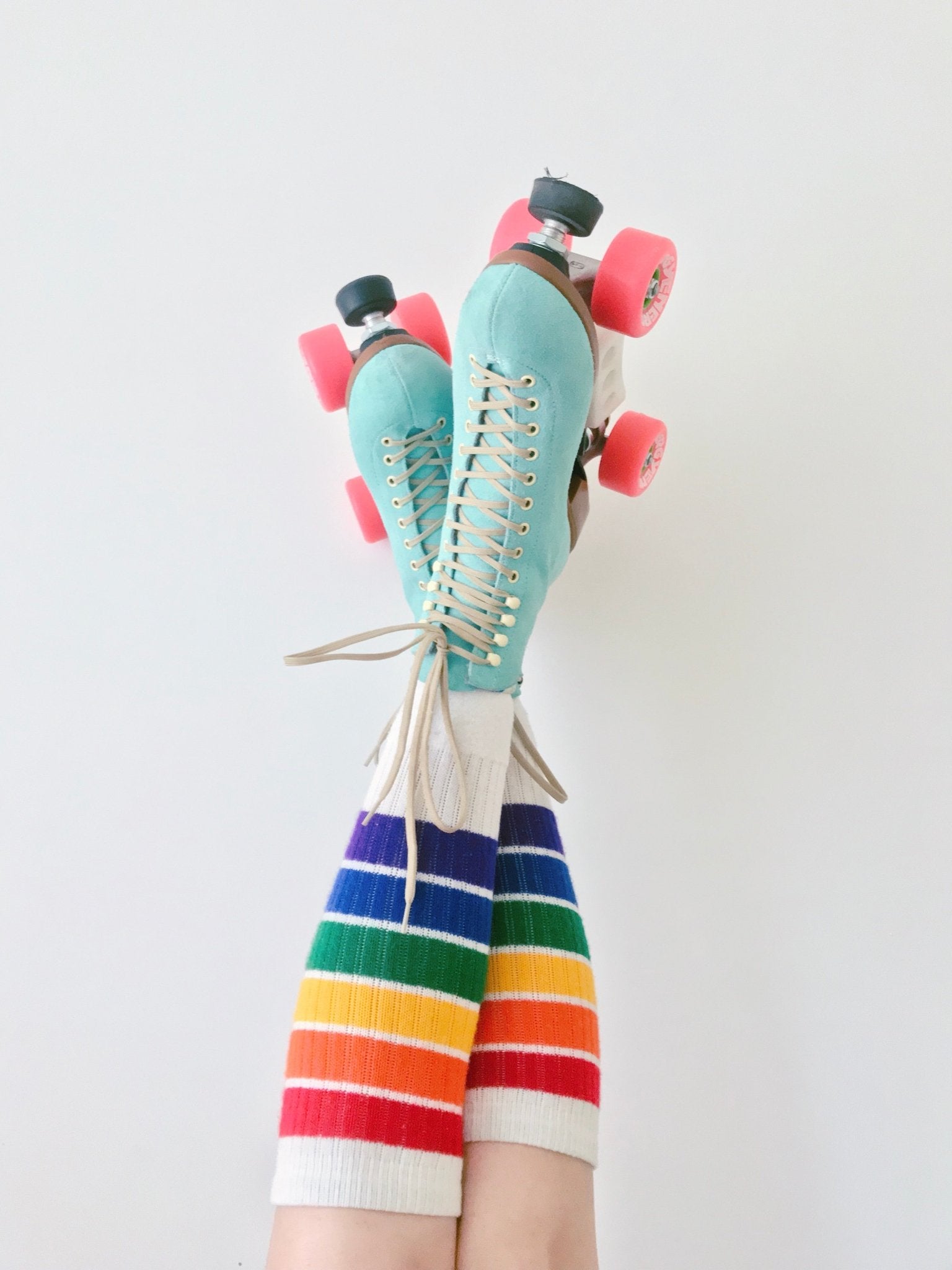 Lifestyle image of YOLO rainbow tube socks with streetwear outfit and roller skates