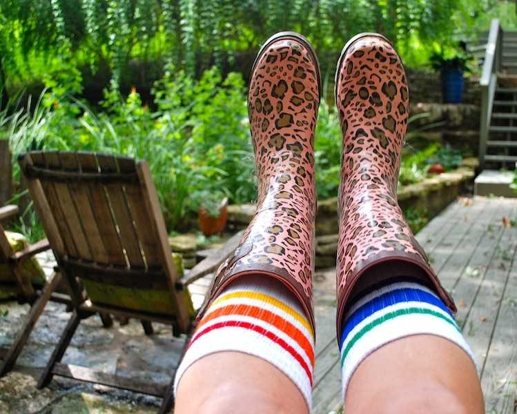 Courage rainbow tube socks styled with rain boots in the backyard