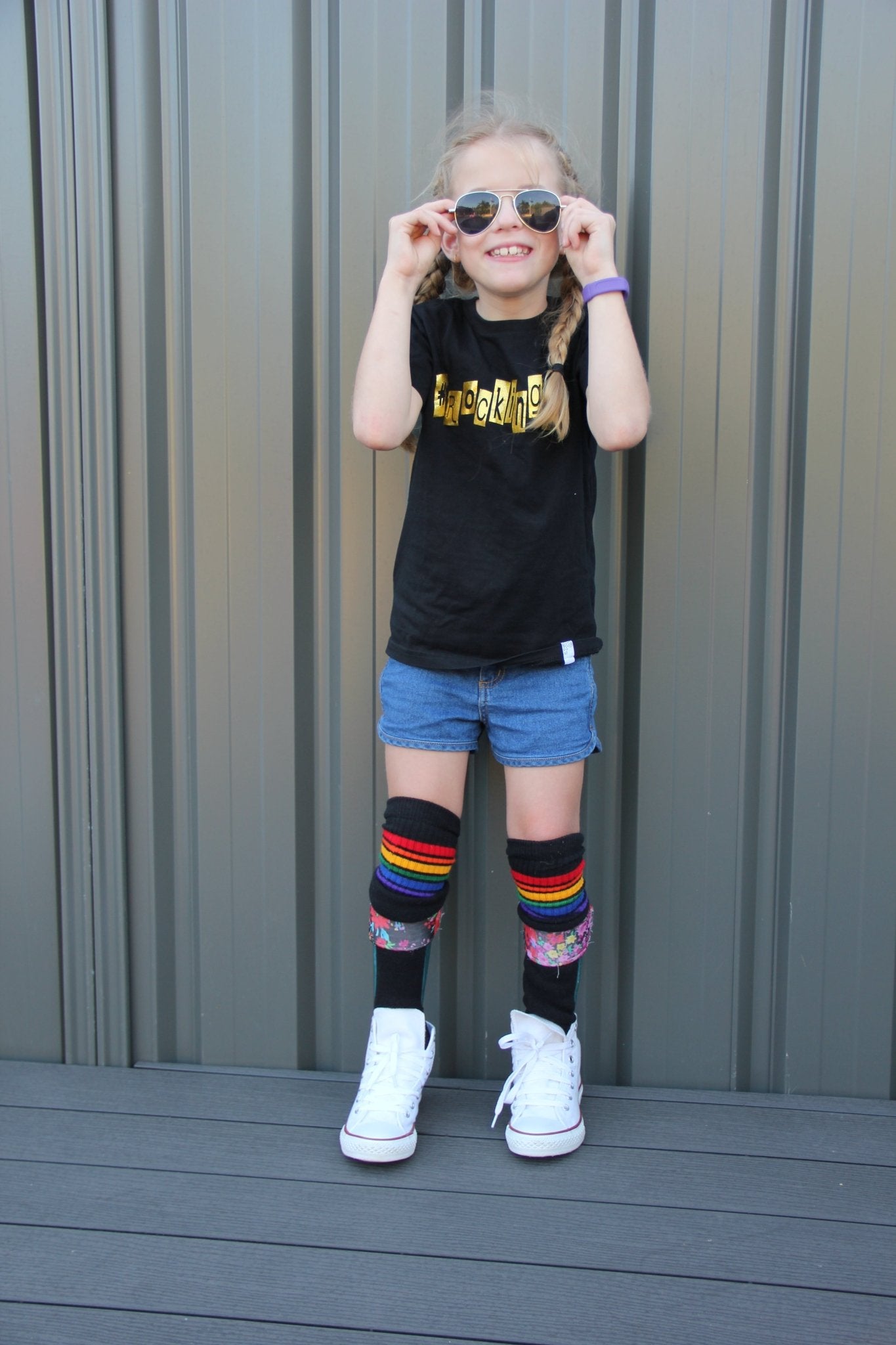 Person wearing Brave rainbow knee high socks with casual outfit and leg braces for support