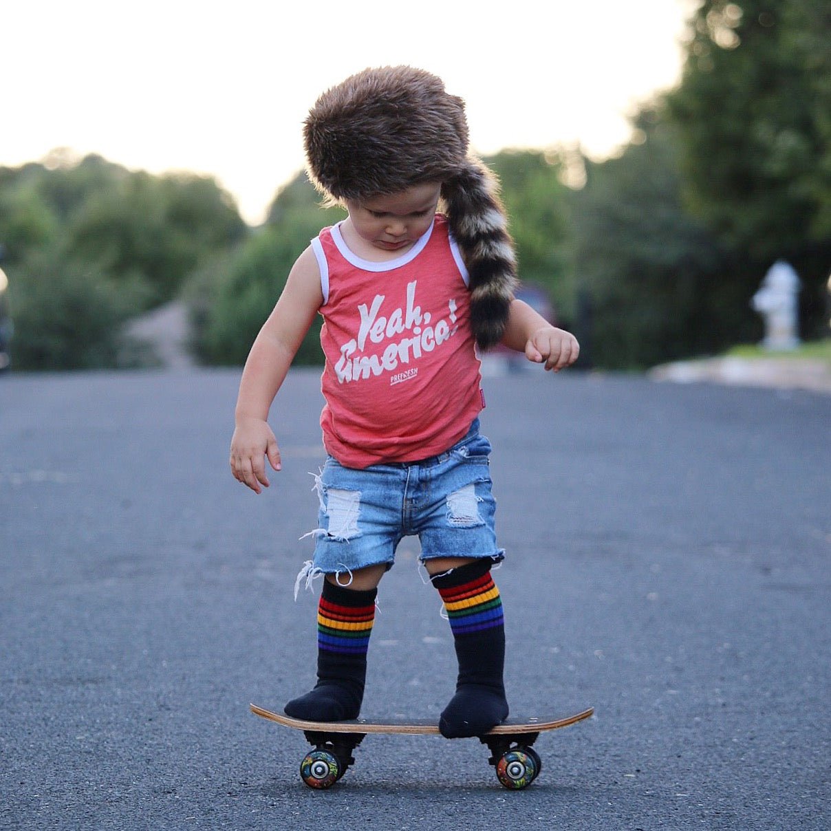 Baby wearing colorful Brave rainbow socks while standing on a skateboard