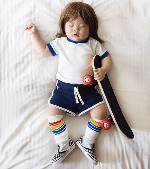 Baby wearing rainbow striped Fearless tube socks while sleeping with skateboard