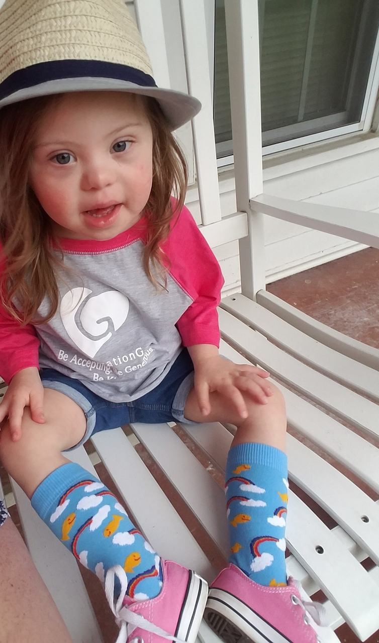 Baby girl rocking out her pride socks designed by rubys rainbow to help students with down syndrome attend college.