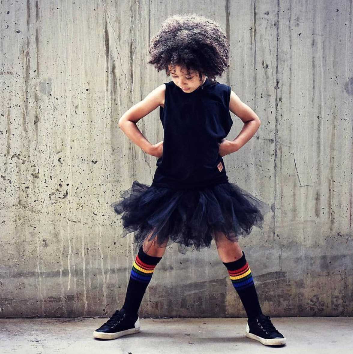 Colorful Brave rainbow socks by Pride Socks while modeling her black dress