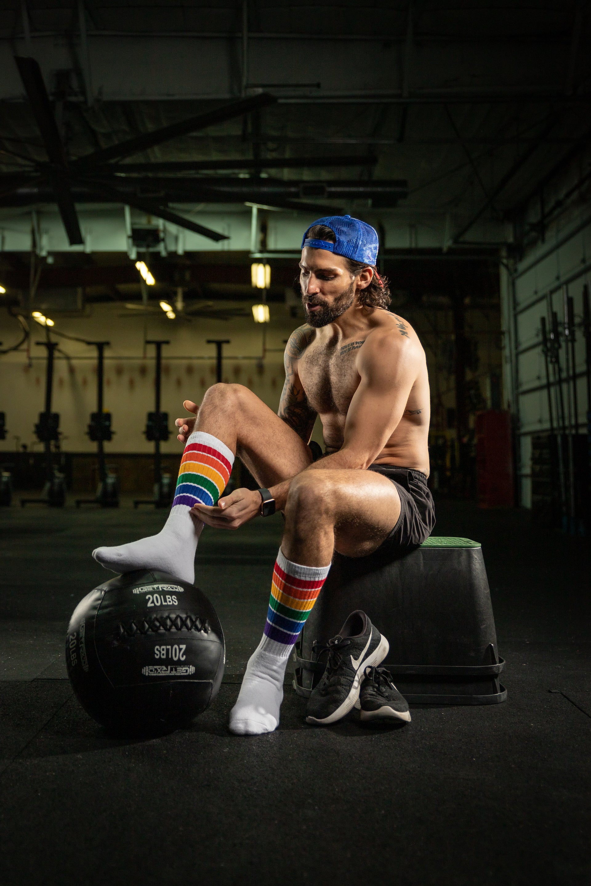 Man sitting on a weight with rainbow socks in a gym setting