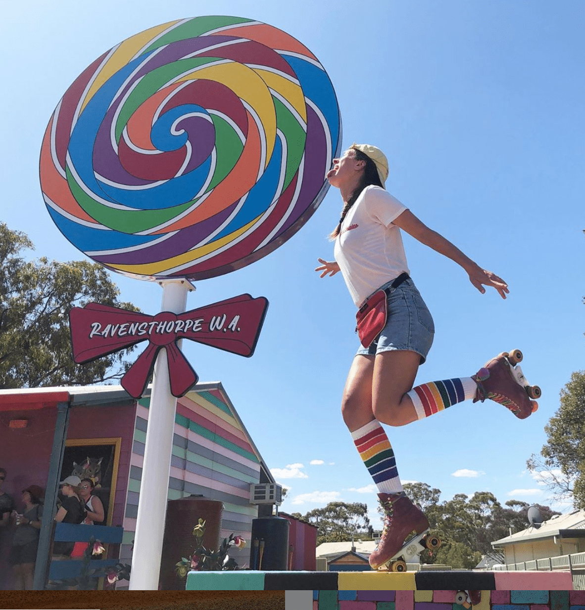 Person wearing YOLO rainbow knee high socks at festival with a rainbow sucker with roller skates
