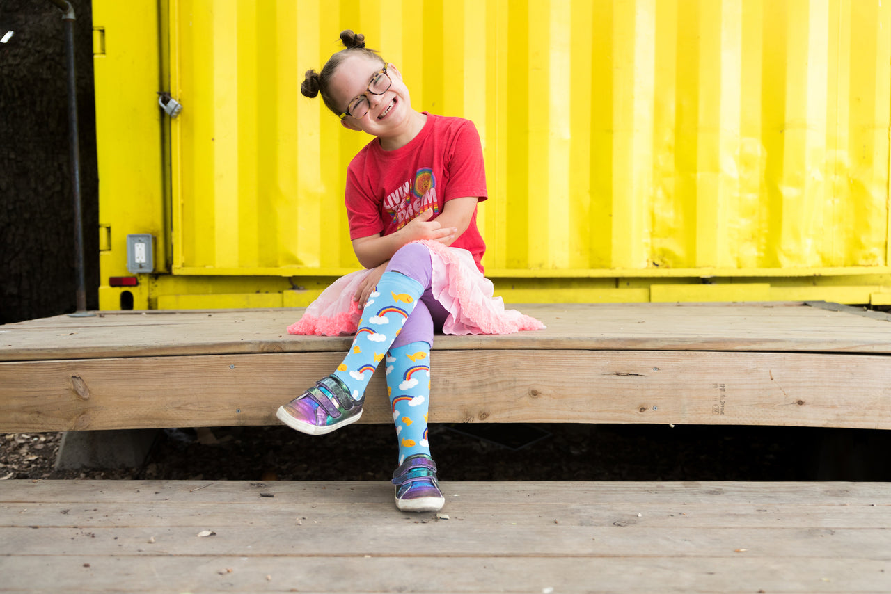 ruby of rubys rainbow showing off her dream big pride socks that help those with Down syndrome to attend college.