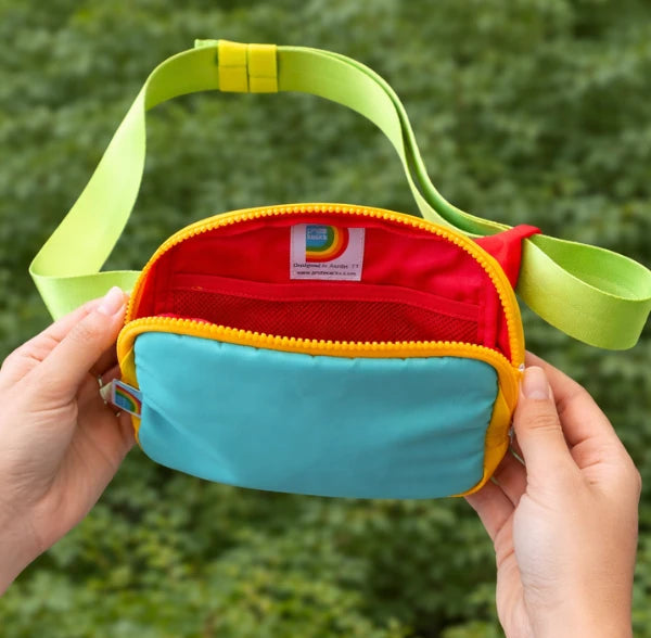 Colorful waist bag held by hands with a green leafy background