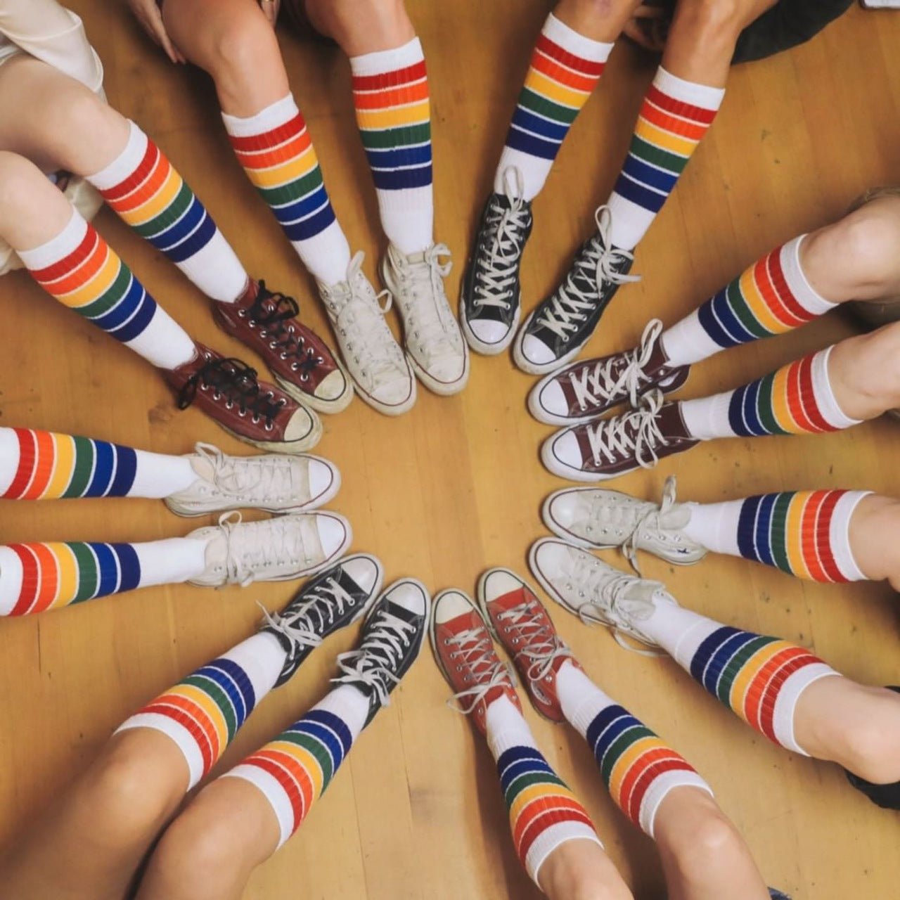 group of friends wearing YOLO rainbow knee high socks in a circle
